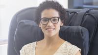 Smiling patient wearing eye glasses and sitting in a chair